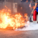Person using a fire extinguisher to put out a fire during a safety training session.