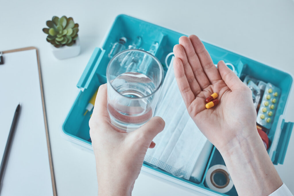 Medical pills in the hand and glass of water. Healthcare and med